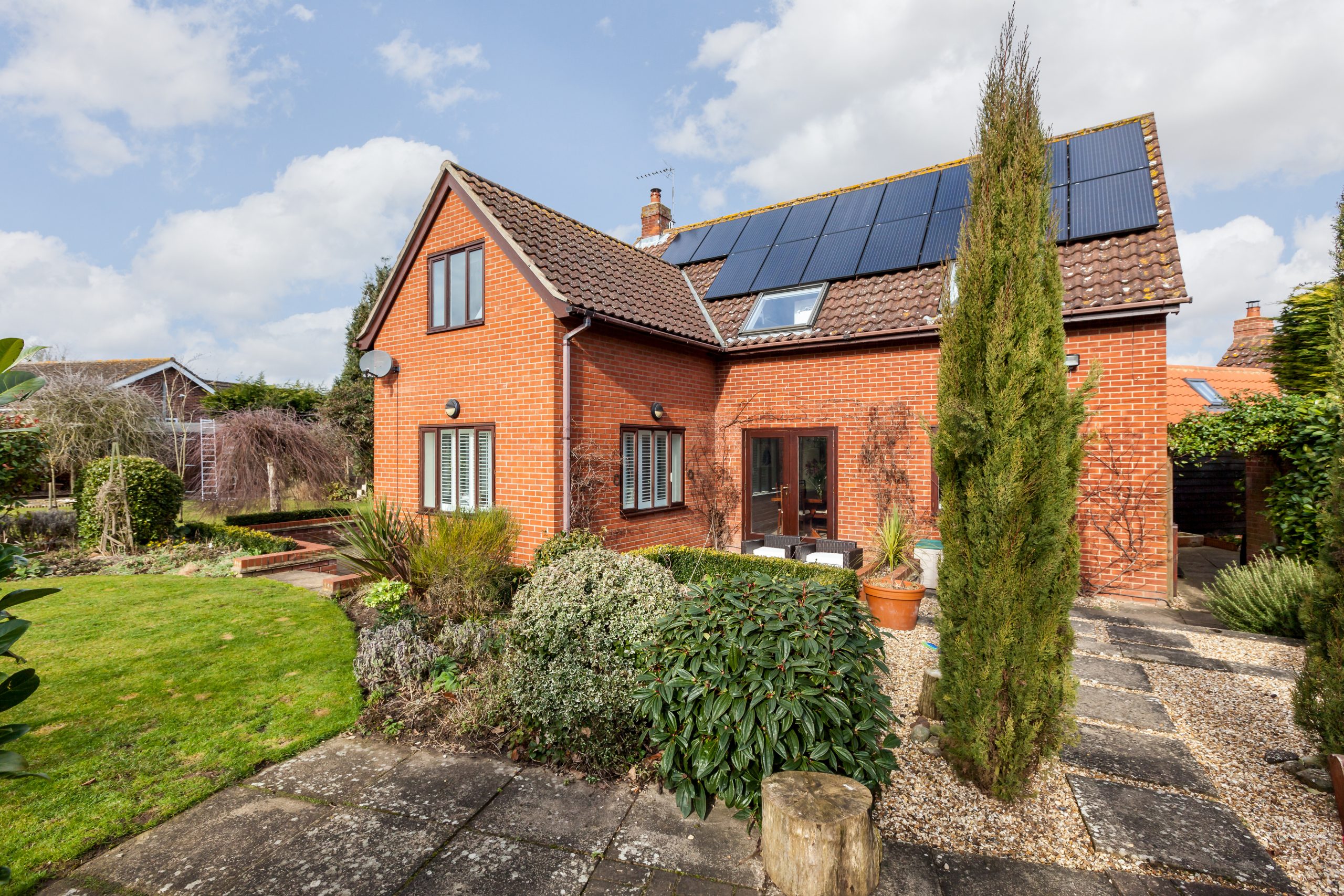 Moulton, Suffolk, England - Feb 19 2015: Traditional detached brick home within landscaped gardens with array of roof mounted photovoltaic solar panels